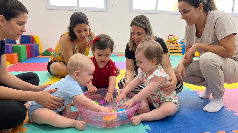 Bebês brincando juntos na água, com os pais por perto